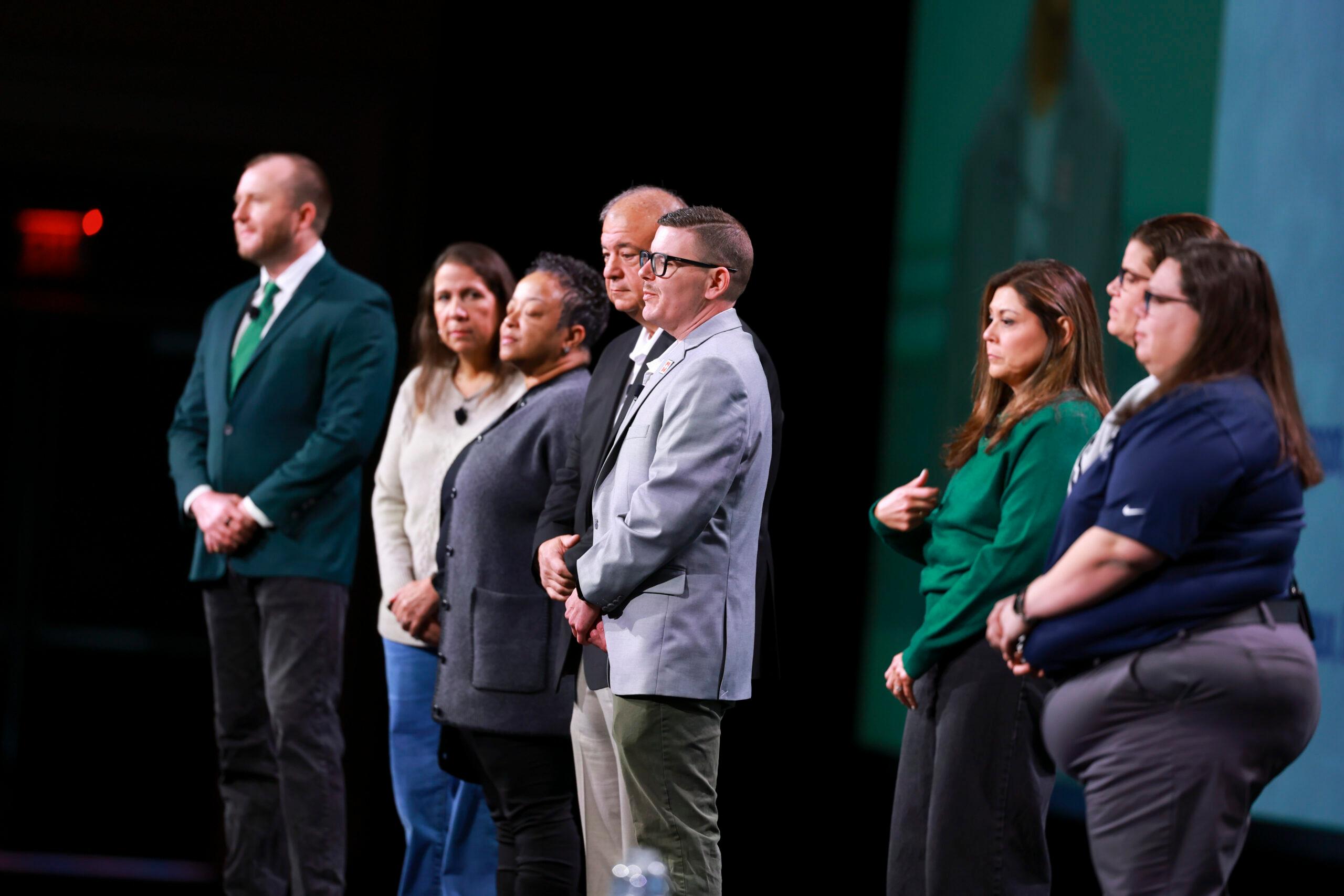 8 people standing on a stage